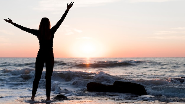 Mujer de vista trasera mirando la puesta de sol con espacio de copia