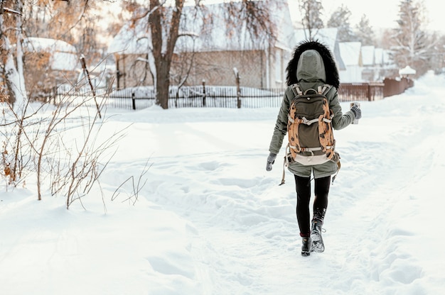 Mujer de vista trasera con mochila en día de invierno