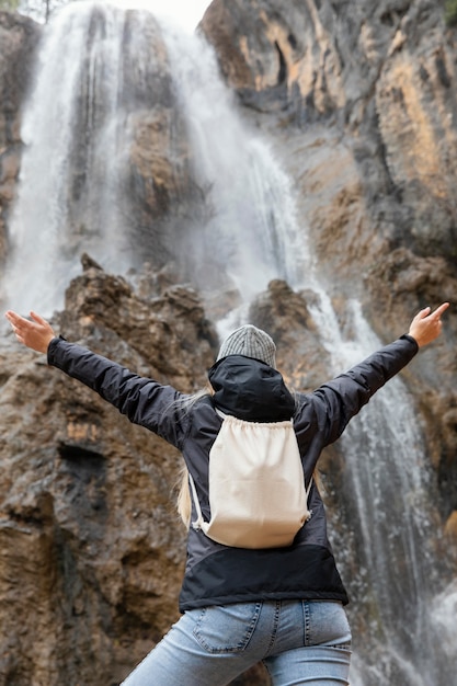 Mujer de vista trasera en la naturaleza en cascada