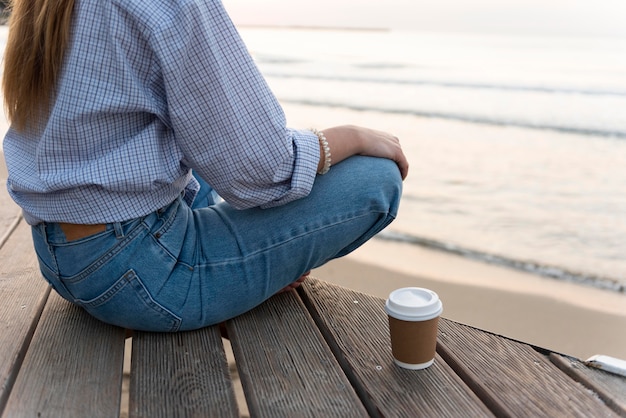 Mujer de vista trasera sentada junto al mar