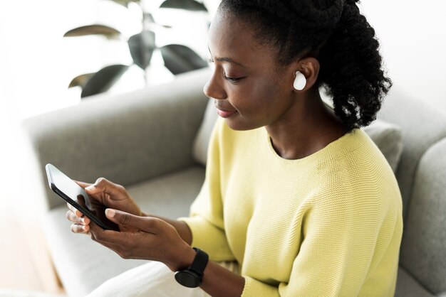 Mujer vistiendo auriculares inalámbricos y usando un teléfono móvil