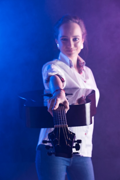 Mujer vistiendo camisa de oficina mostrando una guitarra acústica