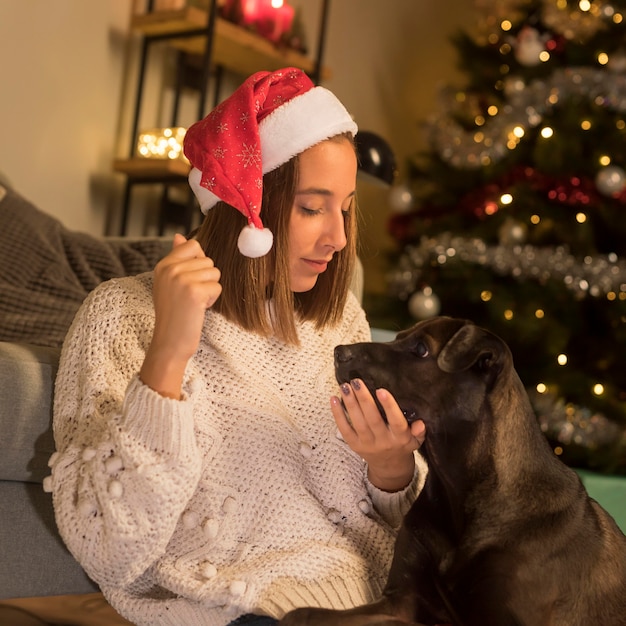 Mujer vistiendo gorro de Papá Noel en Navidad y su perro
