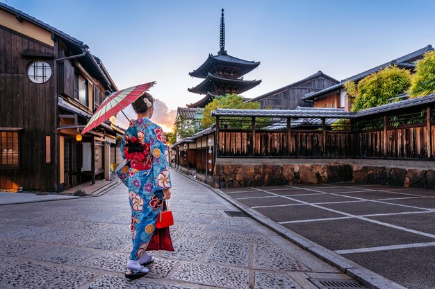 Mujer vistiendo un kimono tradicional japonés con paraguas en la Pagoda Yasaka y la calle Sannen Zaka en Kyoto, Japón.