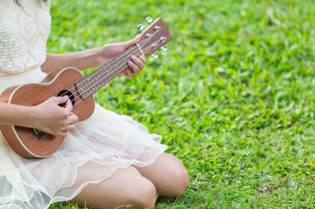 Mujer vistiendo un lindo vestido blanco y tocando el ukelele