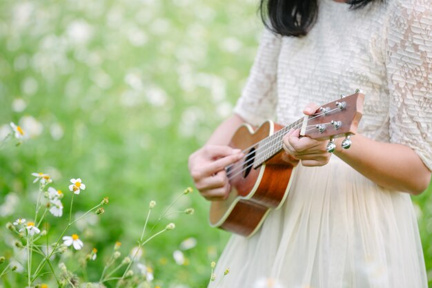 Mujer vistiendo un lindo vestido blanco y tocando el ukelele