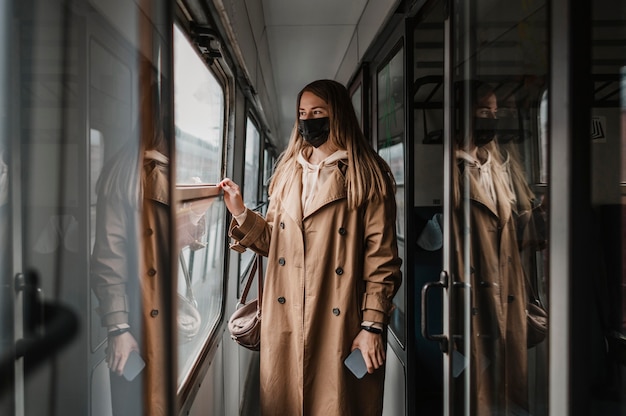 Foto gratuita mujer vistiendo máscara médica en un tren