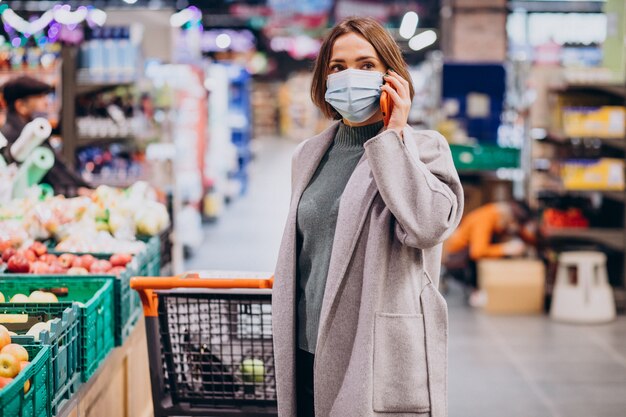 Mujer vistiendo mascarilla y compras en la tienda de comestibles