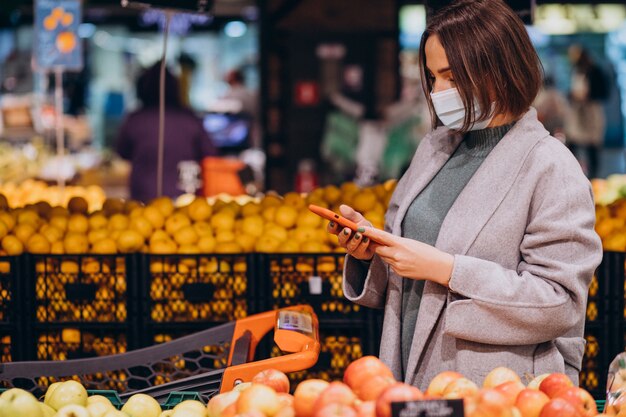 Mujer vistiendo mascarilla y compras en la tienda de comestibles