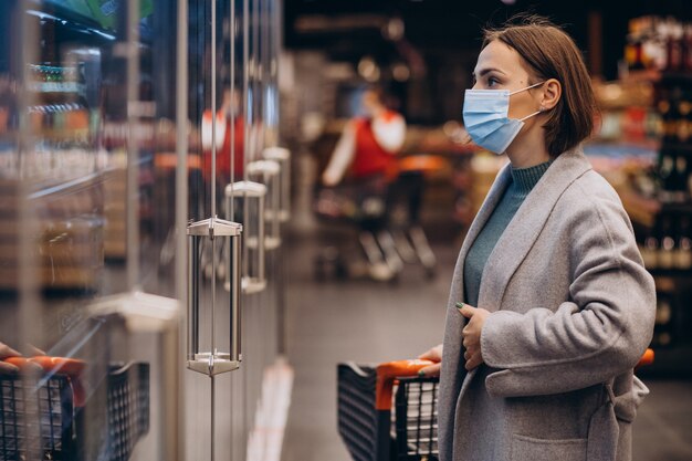 Mujer vistiendo mascarilla y compras en la tienda de comestibles