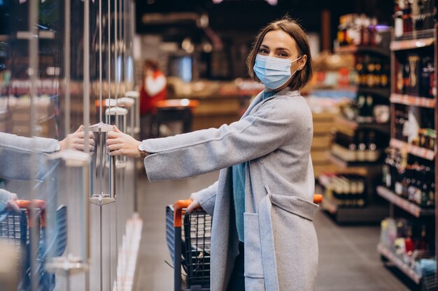 Mujer vistiendo mascarilla y compras en la tienda de comestibles