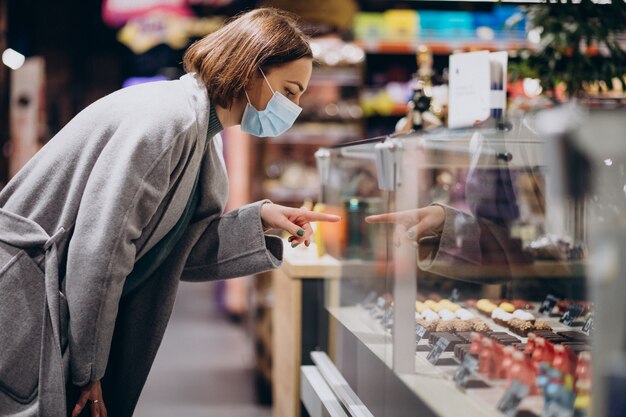 Mujer vistiendo mascarilla y compras en la tienda de comestibles