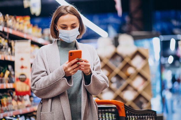 Mujer vistiendo mascarilla y compras en la tienda de comestibles