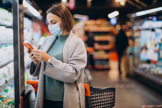 Mujer vistiendo mascarilla y compras en la tienda de comestibles