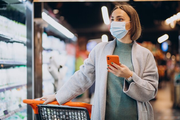 Mujer vistiendo mascarilla y compras en la tienda de comestibles