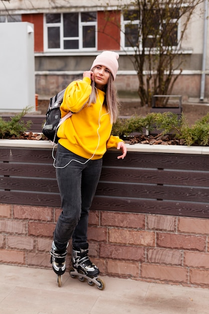 Foto gratuita mujer vistiendo patines posando con gorro y mochila