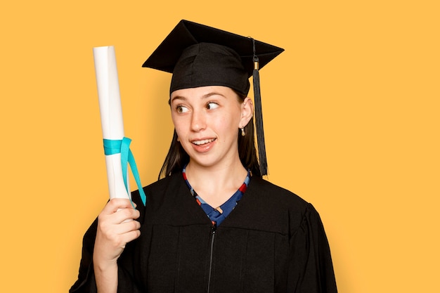 Foto gratuita mujer vistiendo regalia sosteniendo su título de graduación