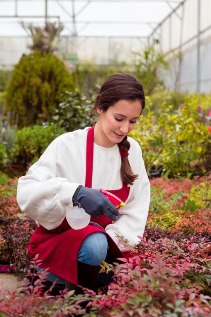 Mujer vistiendo ropas de jardinería rociando plantas