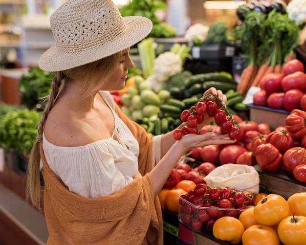 Mujer vistiendo sombrero para el sol con tomates cherry