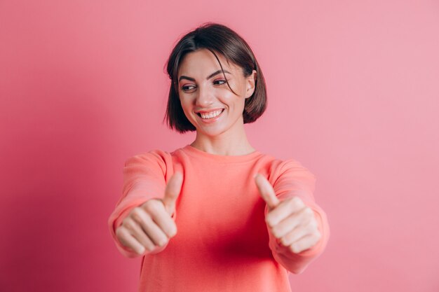 Mujer vistiendo un suéter casual en el fondo aprobando haciendo un gesto positivo con la mano, pulgares arriba sonriendo y feliz por el éxito