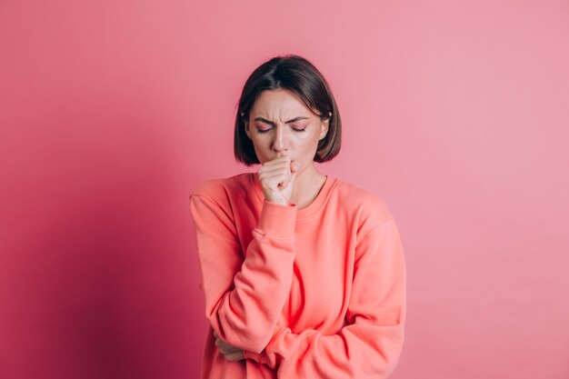 Mujer vistiendo un suéter casual sobre fondo sintiéndose mal y tosiendo como síntoma de resfriado o bronquitis. Concepto de salud.