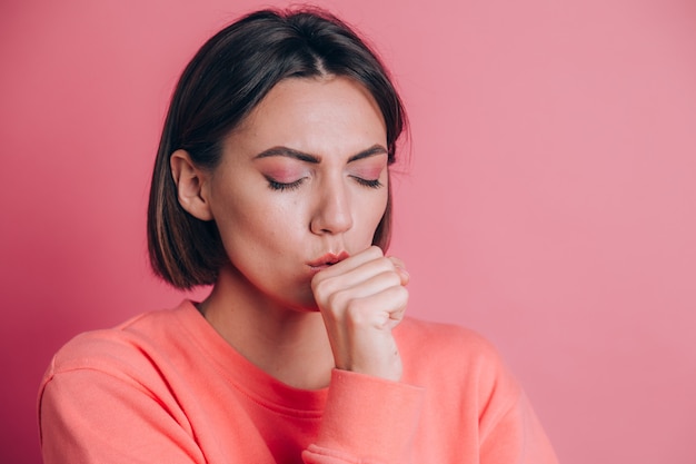 Mujer vistiendo un suéter casual sobre fondo sintiéndose mal y tosiendo como síntoma de resfriado o bronquitis. Concepto de salud.