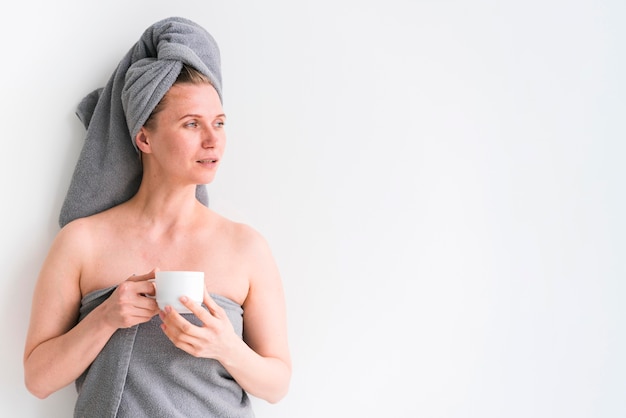 Mujer vistiendo toallas y sosteniendo una taza copia espacio