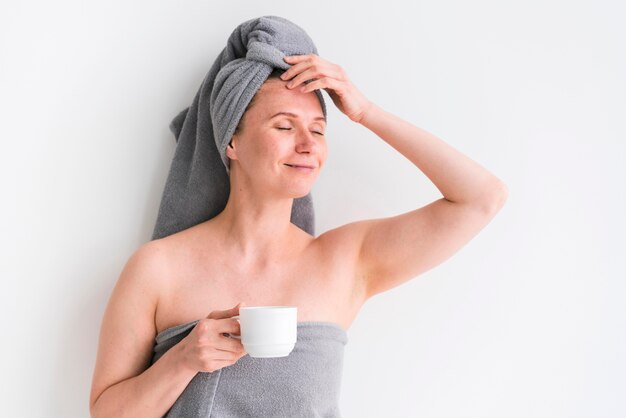 Mujer vistiendo toallas y sosteniendo una taza