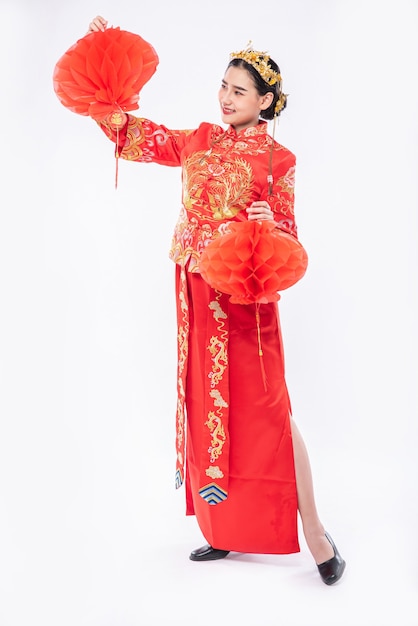 Foto gratuita mujer vistiendo traje cheongsam mostrar decorar lámpara roja en su tienda en año nuevo chino