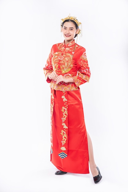 Mujer vistiendo traje Cheongsam sonríe para dar la bienvenida al viajero en un evento del año nuevo chino
