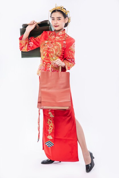Mujer vistiendo traje Cheongsam sonrisa con bolsa de papel de compras en año nuevo chino