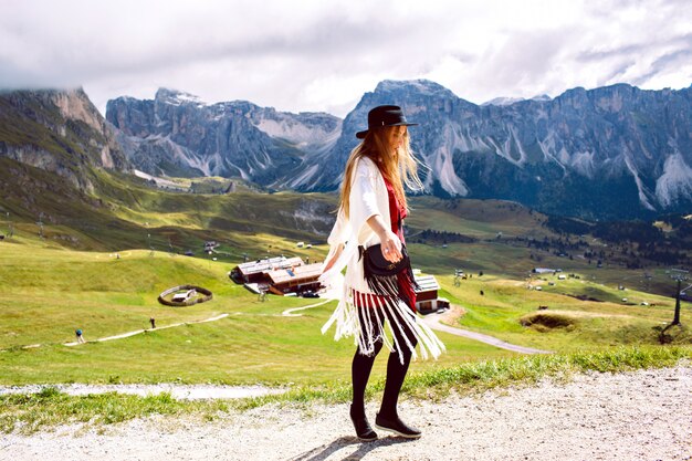 Mujer vistiendo traje elegante boho, caminando sola y disfrutando de impresionantes vistas de las montañas alpinas austriacas