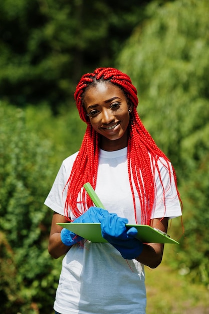 Foto gratuita mujer voluntaria pelirroja africana con portapapeles en el parque áfrica voluntariado personas caritativas y concepto de ecología