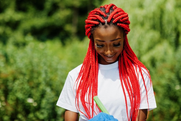 Mujer voluntaria pelirroja africana con portapapeles en el parque África voluntariado personas caritativas y concepto de ecología
