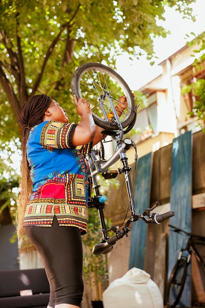 Foto gratuita mujer volviendo a conectar la rueda de la bicicleta en el patio