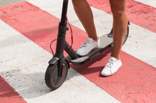 Mujer con zapatillas de tenis montando scooter