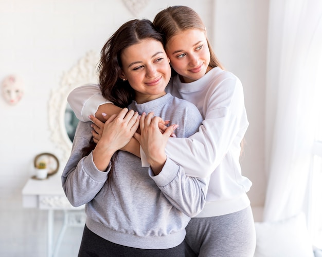 Foto gratuita mujeres abrazándose y apartando la mirada.