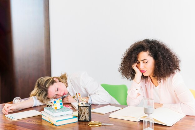 Mujeres aburridas que duermen durante el estudio