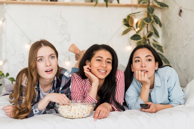 Mujeres acostadas en la cama y viendo la televisión.