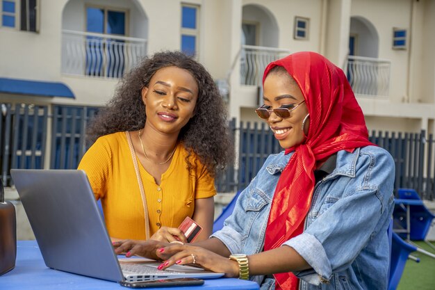 Mujeres africanas de compras en línea mientras está sentado en un café