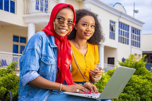 Mujeres africanas de compras en línea mientras está sentado en un parque