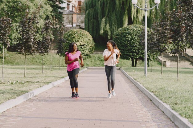 Mujeres africanas jóvenes sanas al aire libre en el parque de la mañana. Entrenamiento de amigos.