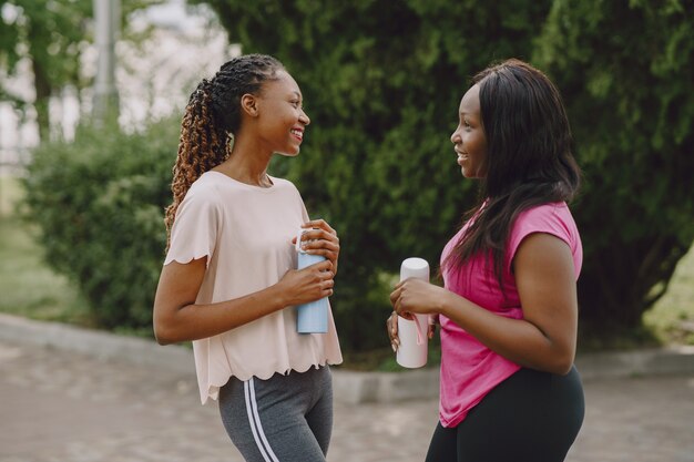 Mujeres africanas jóvenes sanas al aire libre en el parque de la mañana. Entrenamiento de amigos.