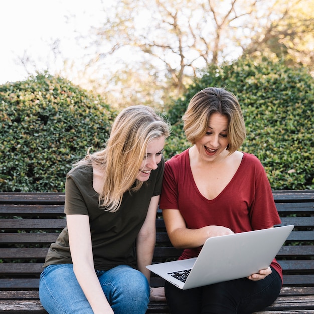 Mujeres alegres apuntando a la pantalla de la computadora portátil