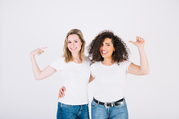 Mujeres alegres apuntando a sí mismos