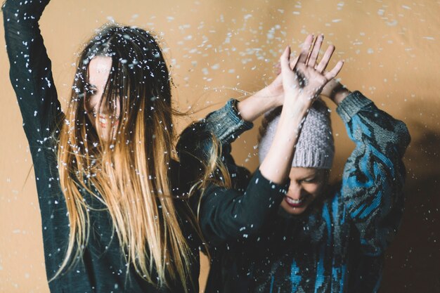 Mujeres alegres bailando bajo la nieve