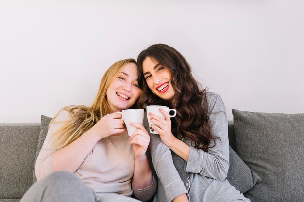 Mujeres alegres bebiendo en el sofá