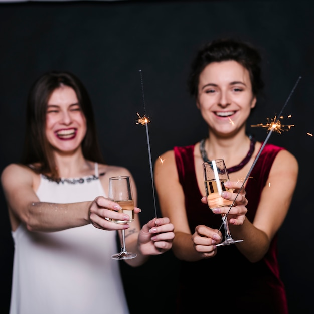 Mujeres alegres con copas de champán y bengalas.