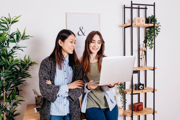 Mujeres alegres coworking en la computadora portátil