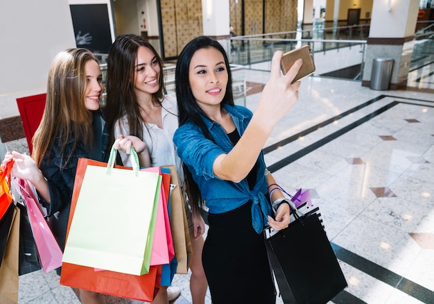 Mujeres alegres posando para selfie en el centro comercial